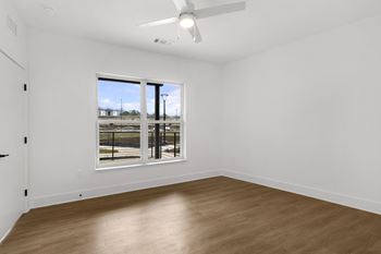 A room with a ceiling fan and a large window overlooking a parking lot.